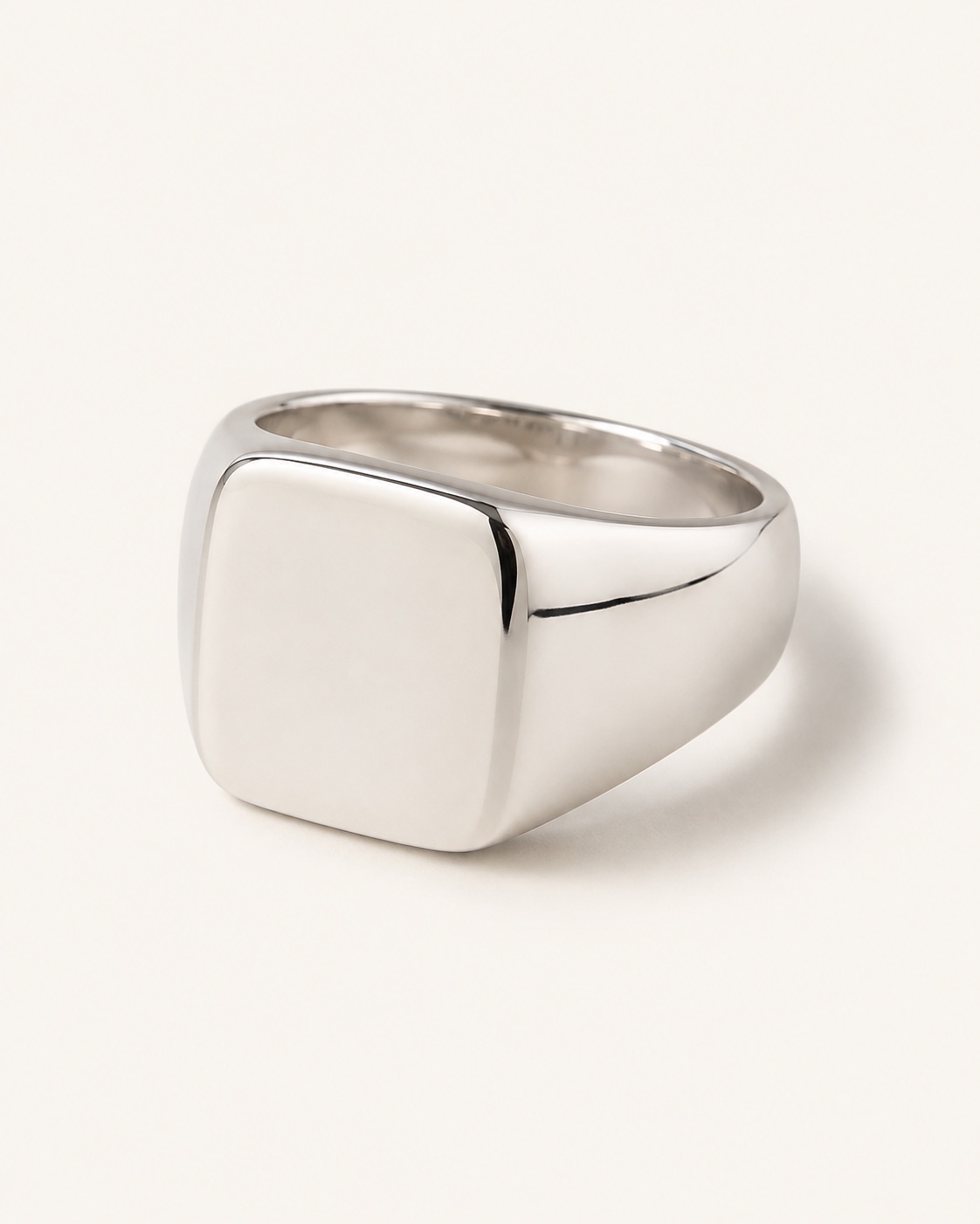 Polished silver Arc Signet Ring on a warm white background
