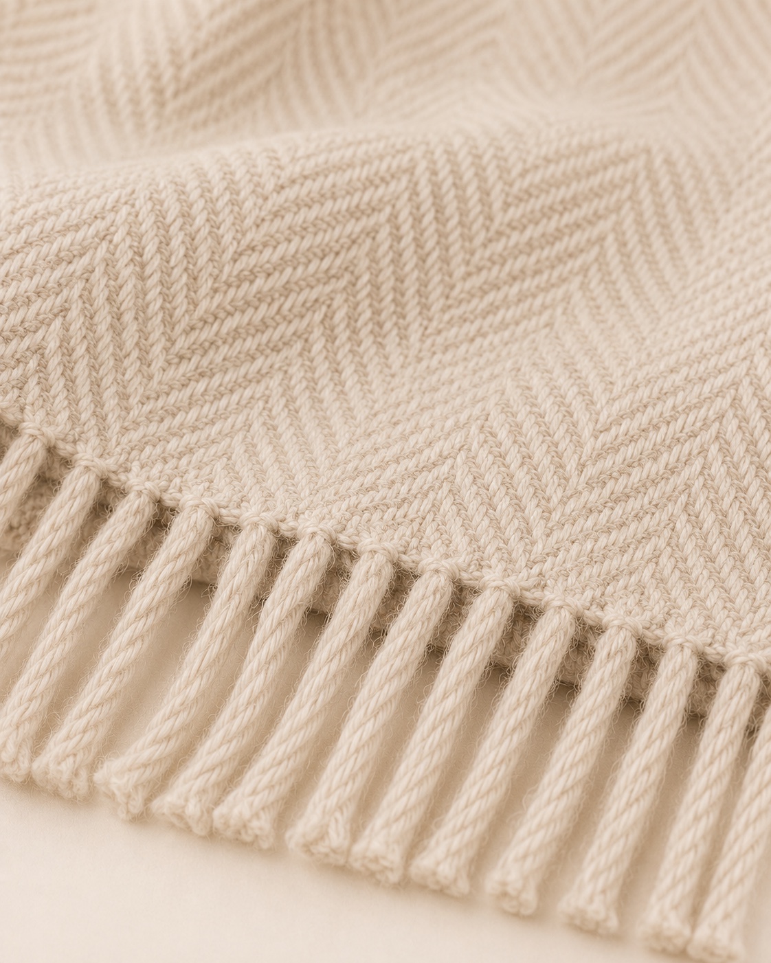 Close view of the oat Woven Throw herringbone weave and twisted fringe